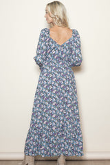 woman wearing a floral long sleeve maxi dress with a v-back and tiered skirt
