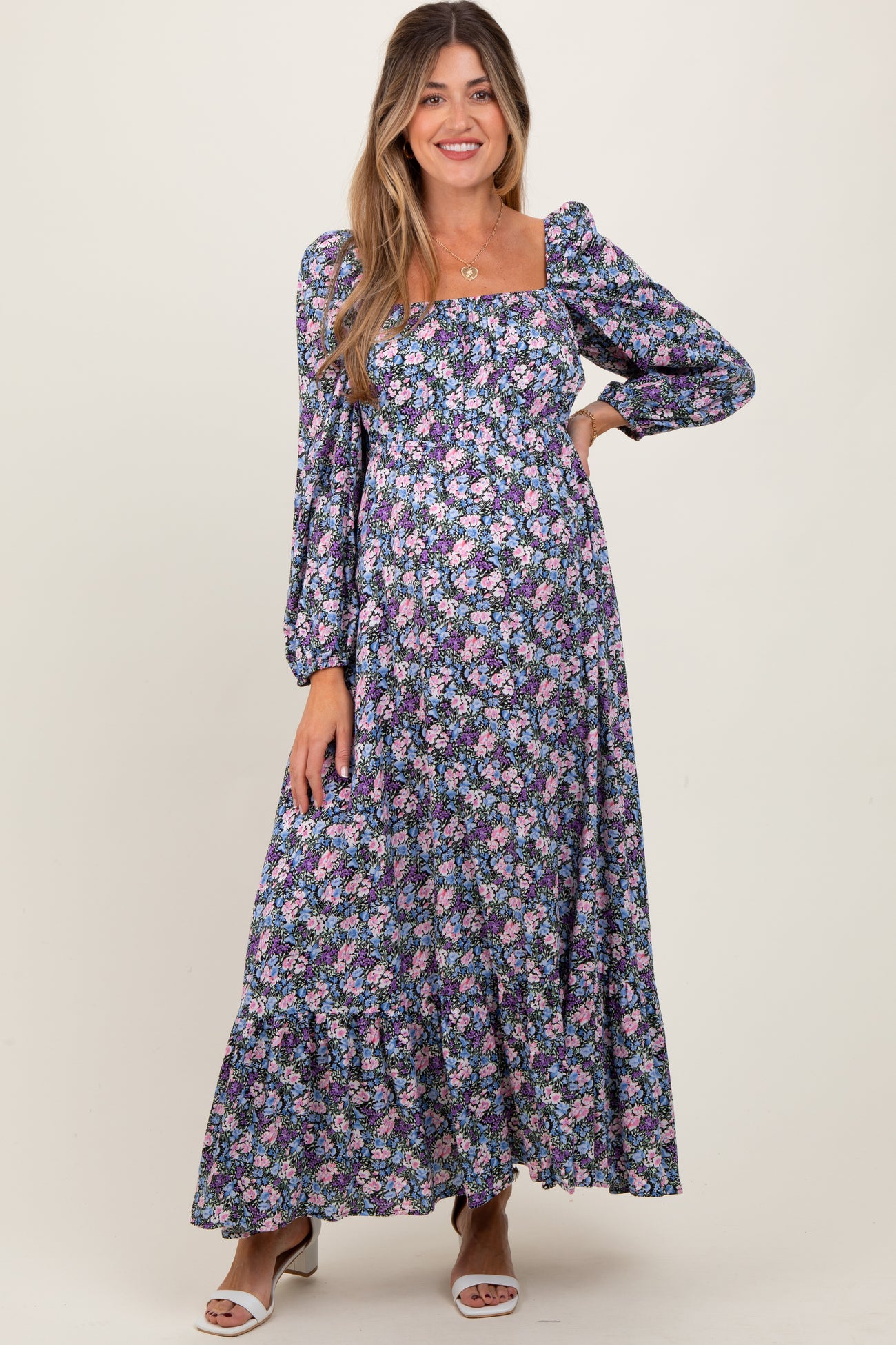 woman wearing a pink and purple floral maternity maxi dress with puff sleeves and a square neckline, showing her baby bump