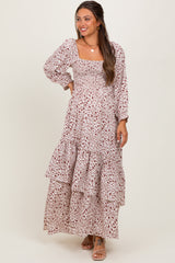 woman wearing a floral print maternity maxi dress with long sleeves and tiered ruffles, smiling while showing off her baby bump