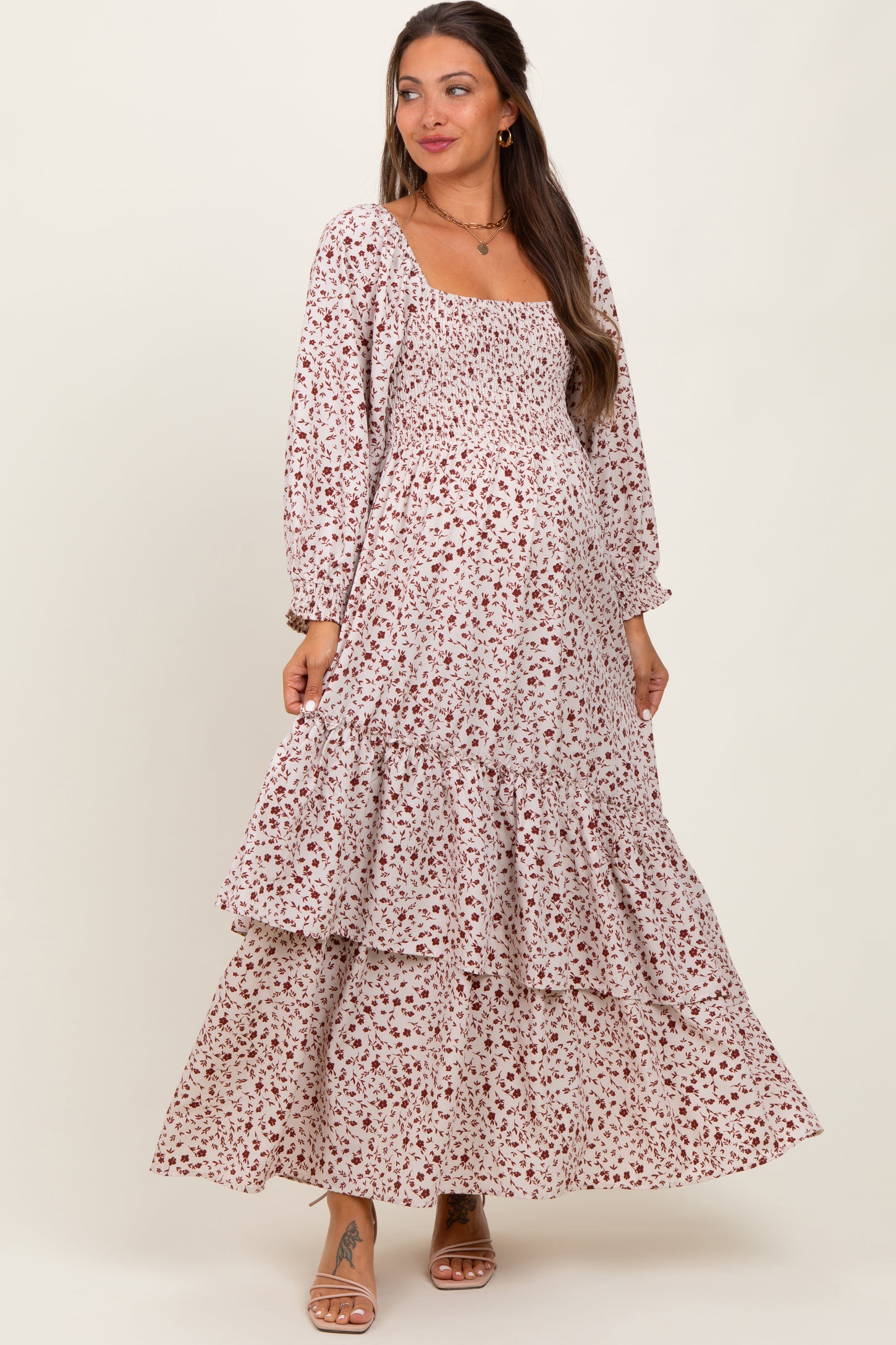 woman wearing a floral print maternity maxi dress with a smocked bodice and tiered ruffles, showing her baby bump