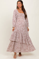 woman wearing a floral print maternity maxi dress with a smocked bodice and tiered ruffles, showing her baby bump