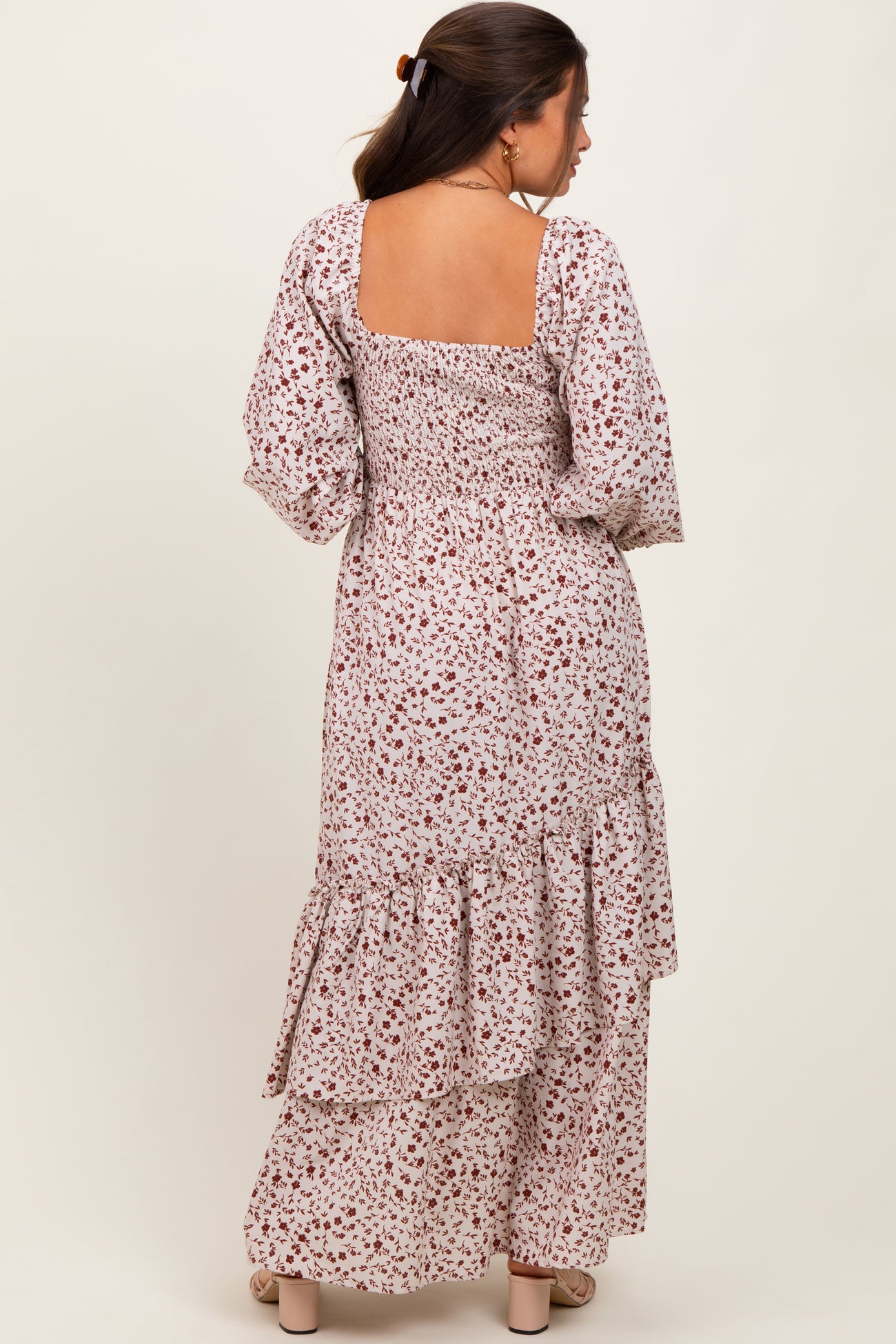woman wearing a floral printed long sleeve maternity dress with a tiered skirt and smocked back detail