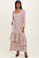 woman wearing a long sleeve floral maxi dress with a square neckline and tiered skirt, standing with one hand in pocket