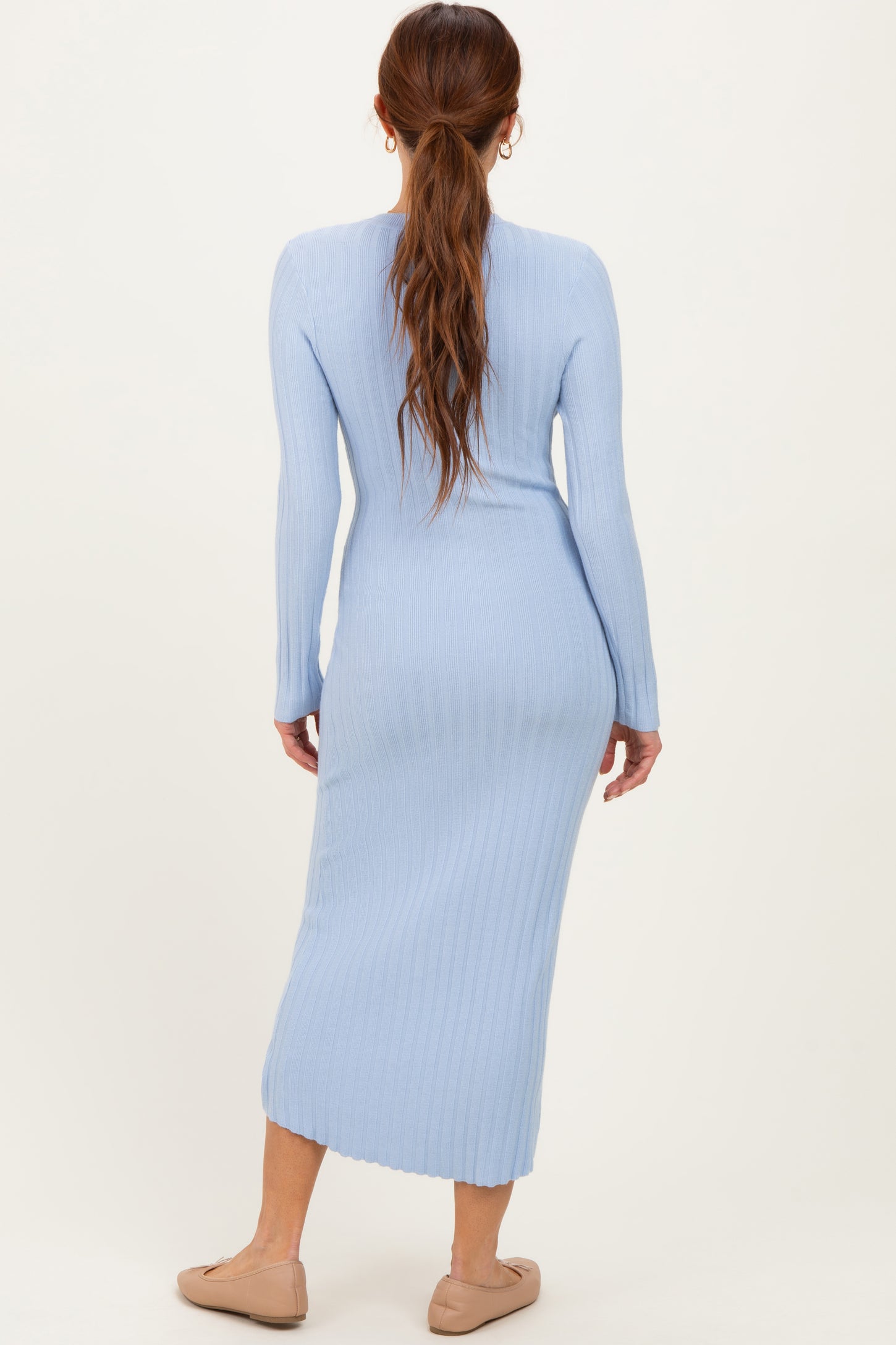 woman wearing a light blue ribbed midi dress with long sleeves and a fitted silhouette, viewed from the back