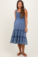 woman wearing a denim blue maternity dress with ruffled tiers and shoulder straps, showcasing a baby bump