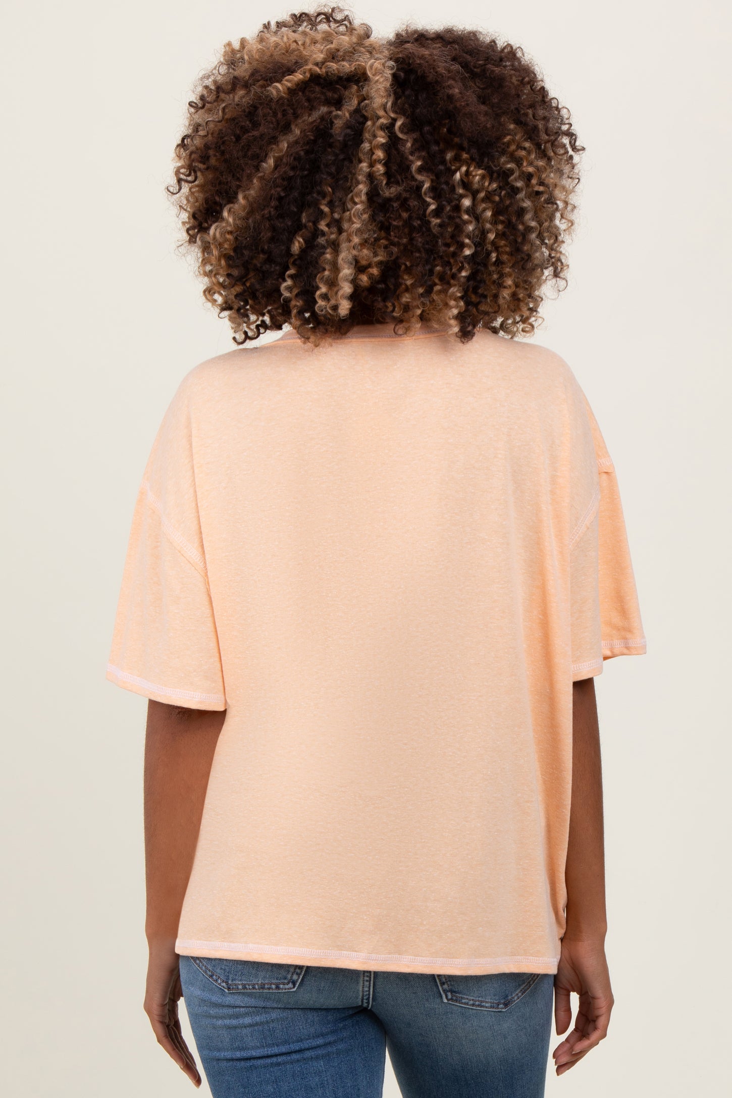 woman wearing a soft peach loose-fitting maternity top with short sleeves, view of the back