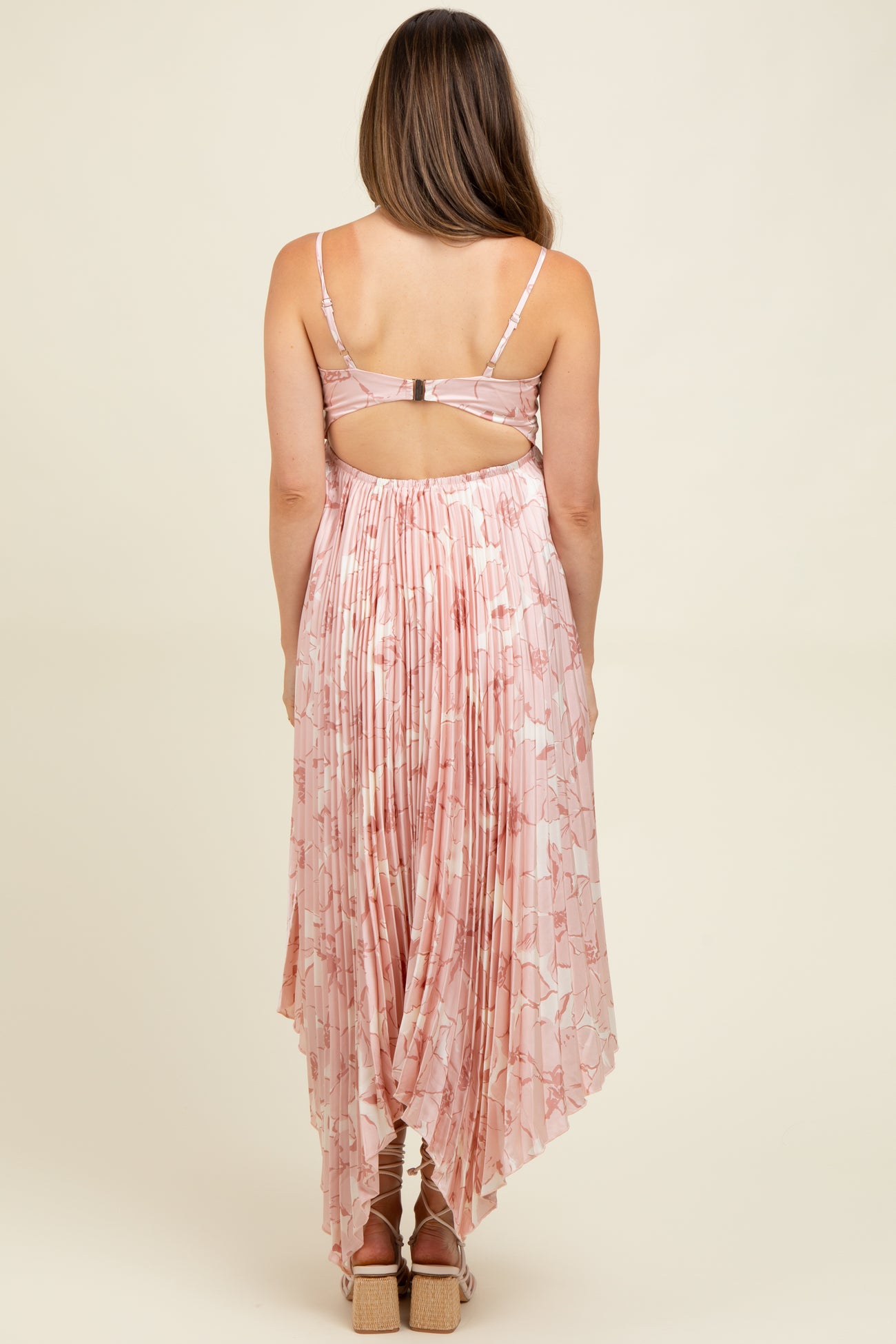 woman wearing a pink floral maternity dress with a pleated back and a high-low hemline