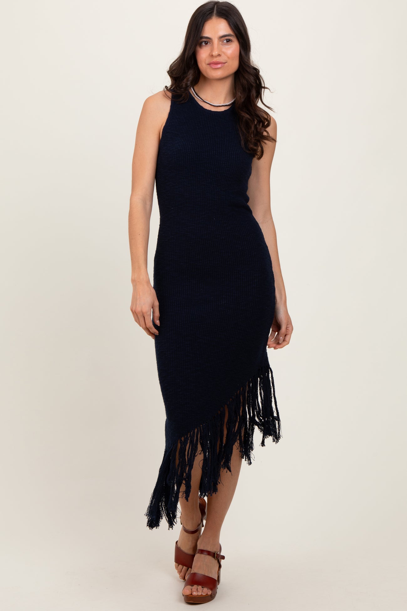 woman wearing a navy blue knitted maxi dress with fringe hem and a fitted silhouette.