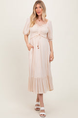 woman wearing a light beige puff sleeve midi dress with smocked bodice and ruffled hem, posing with hands in pockets