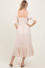 woman wearing a pale pink puff sleeve midi dress with a smocked bodice and ruffled hem, viewed from the back