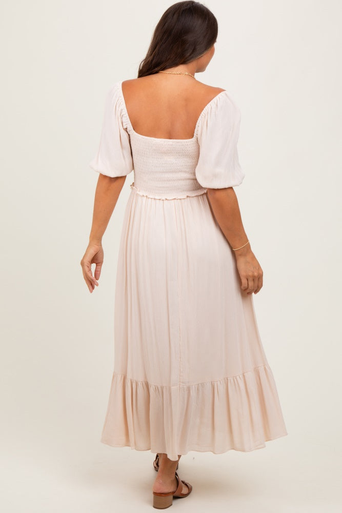 woman wearing a light pink maternity dress with puff sleeves and a smocked bodice, showing the back view