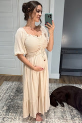 woman wearing a beige maternity maxi dress with smocked bodice and short puff sleeves, showing her baby bump