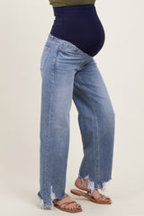 woman wearing light blue distressed maternity jeans with a navy blue over-the-bump waistband and sandals, showing her baby bump