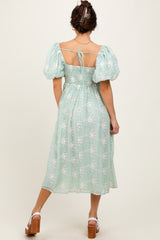 woman wearing a mint green puff sleeve dress with floral embroidery and a tied back detail