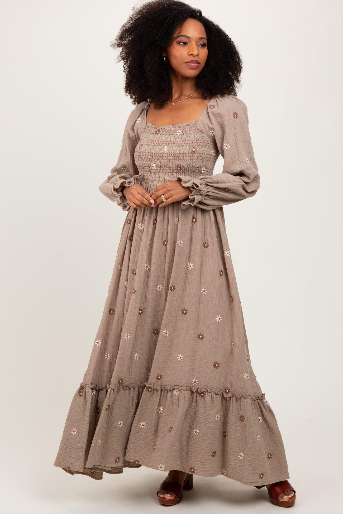 woman wearing a taupe long sleeve maxi dress with floral embroidery and ruffled hem