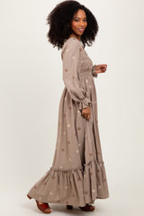 woman wearing a brown floral embroidered maxi dress with long sleeves and a ruffled hem