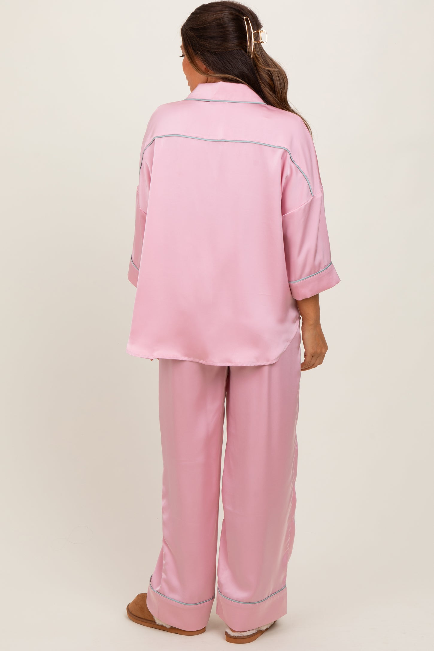 woman wearing a pink satin maternity pajama set with a relaxed fit and contrast piping, viewed from the back