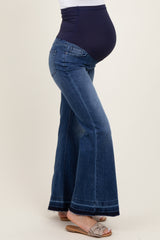 woman wearing a pair of flared maternity jeans with a navy blue over-the-bump panel and visible baby bump