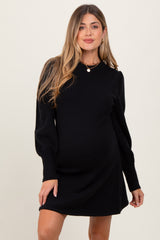 woman wearing a black long sleeve maternity dress showcasing her baby bump