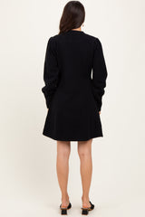 woman wearing a black long sleeve dress with a fitted bodice and flared skirt, viewed from the back