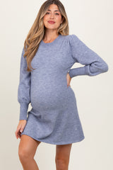 woman wearing a light blue maternity sweater dress with puff sleeves and a visible baby bump