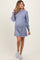woman wearing a light blue maternity sweater dress with puff sleeves and a visible baby bump