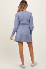 woman wearing a blue knit maternity dress with long sleeves and a fitted waist, showing a baby bump from behind