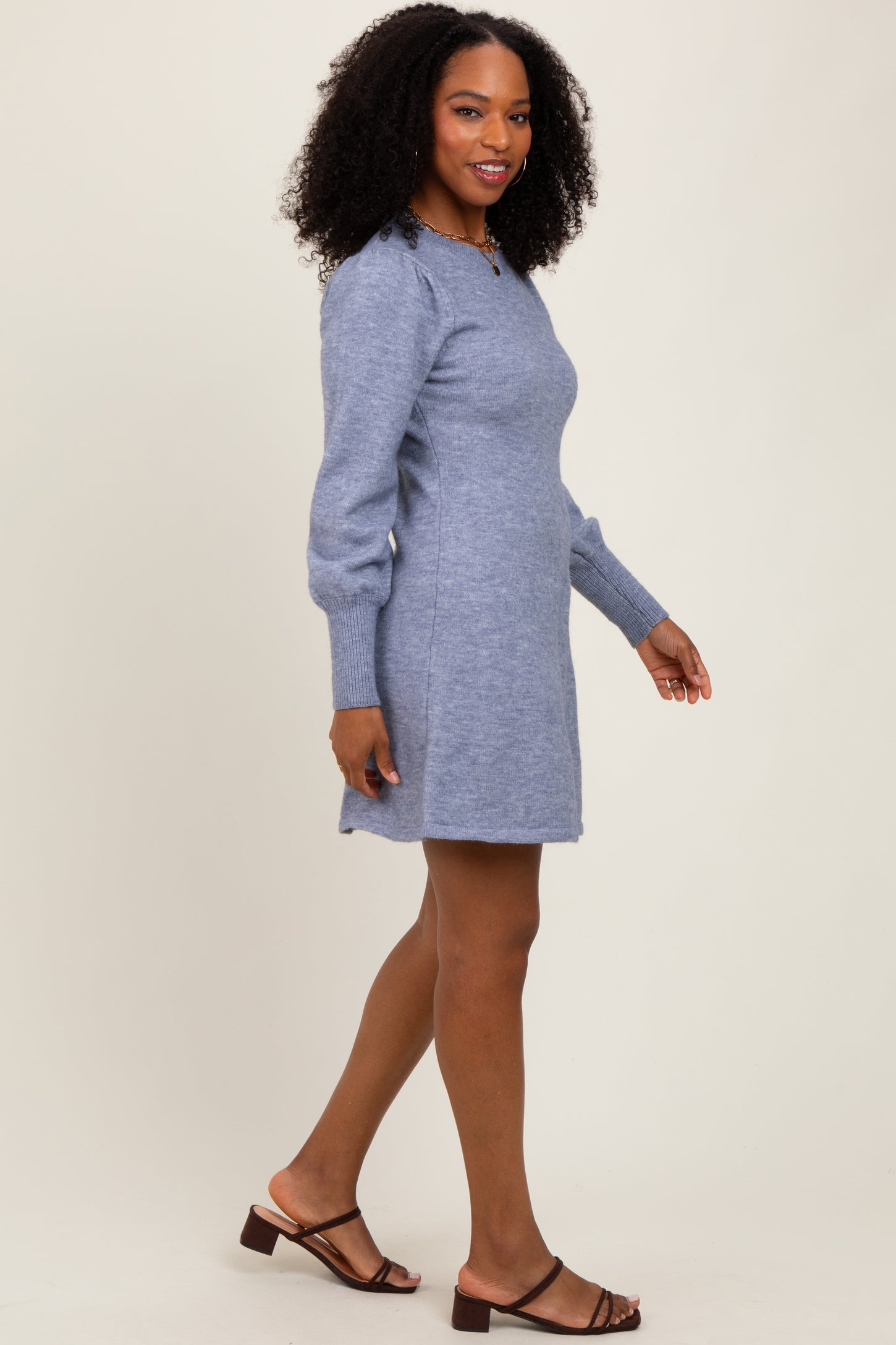 woman wearing a light blue short sweater dress with puff sleeves and brown strappy sandals