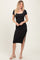 woman wearing a black ribbed midi dress with a square neckline and side slit, standing against a neutral background