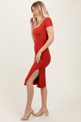woman wearing a rust colored ribbed midi dress with short sleeves and a side slit
