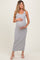 woman wearing a gray and white striped maternity maxi dress and cradling her baby bump