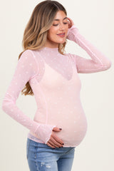 woman wearing a pink long sleeve maternity top with heart patterns and a baby bump visible