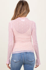 woman wearing a light pink long sleeve maternity top with heart patterns, showing a baby bump from the back