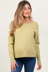 woman wearing a light olive green maternity sweater with long sleeves and relaxed fit, showing baby bump
