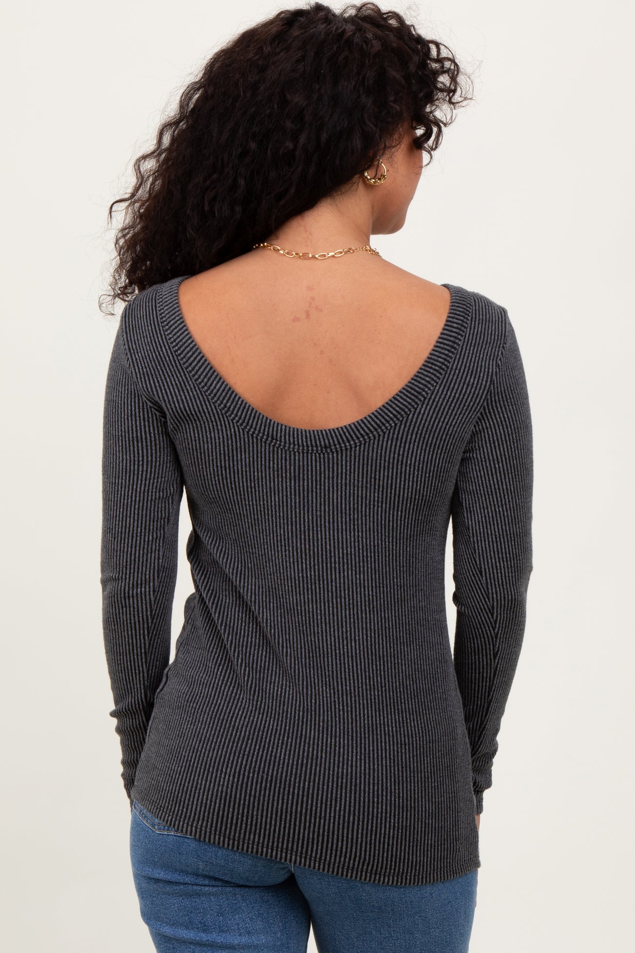woman wearing a gray ribbed top with a low back and long sleeves, shown from the back