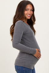 woman wearing a gray ribbed long sleeve maternity top and holding her baby bump