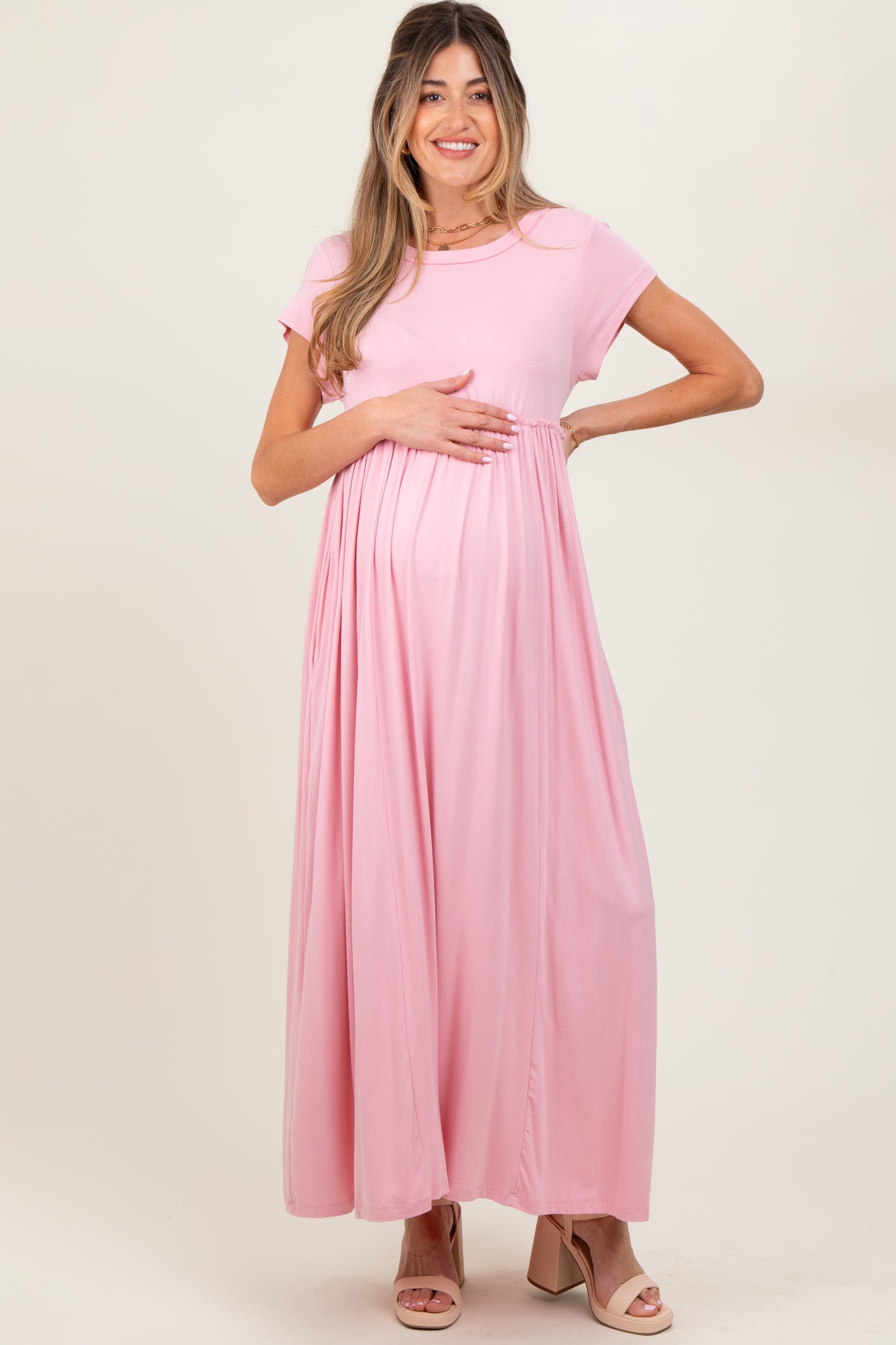 woman wearing a pink short sleeve maternity maxi dress and holding her baby bump