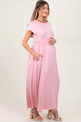 woman wearing a light pink maternity maxi dress with pockets and a visible baby bump