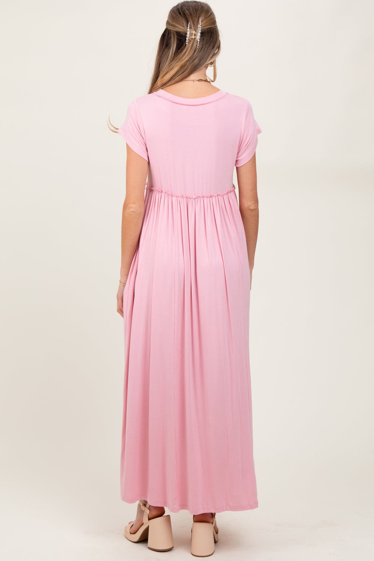 woman wearing a pink maternity maxi dress with short sleeves and an empire waist, showing a baby bump