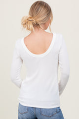 woman wearing a white long sleeve ribbed top with a deep scoop back, styled with blue jeans