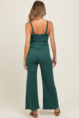 woman wearing a green ribbed maternity jumpsuit with a smocked bodice and wide-leg pants, shown from the back