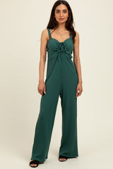woman wearing a green ribbed jumpsuit with a front tie detail and spaghetti straps