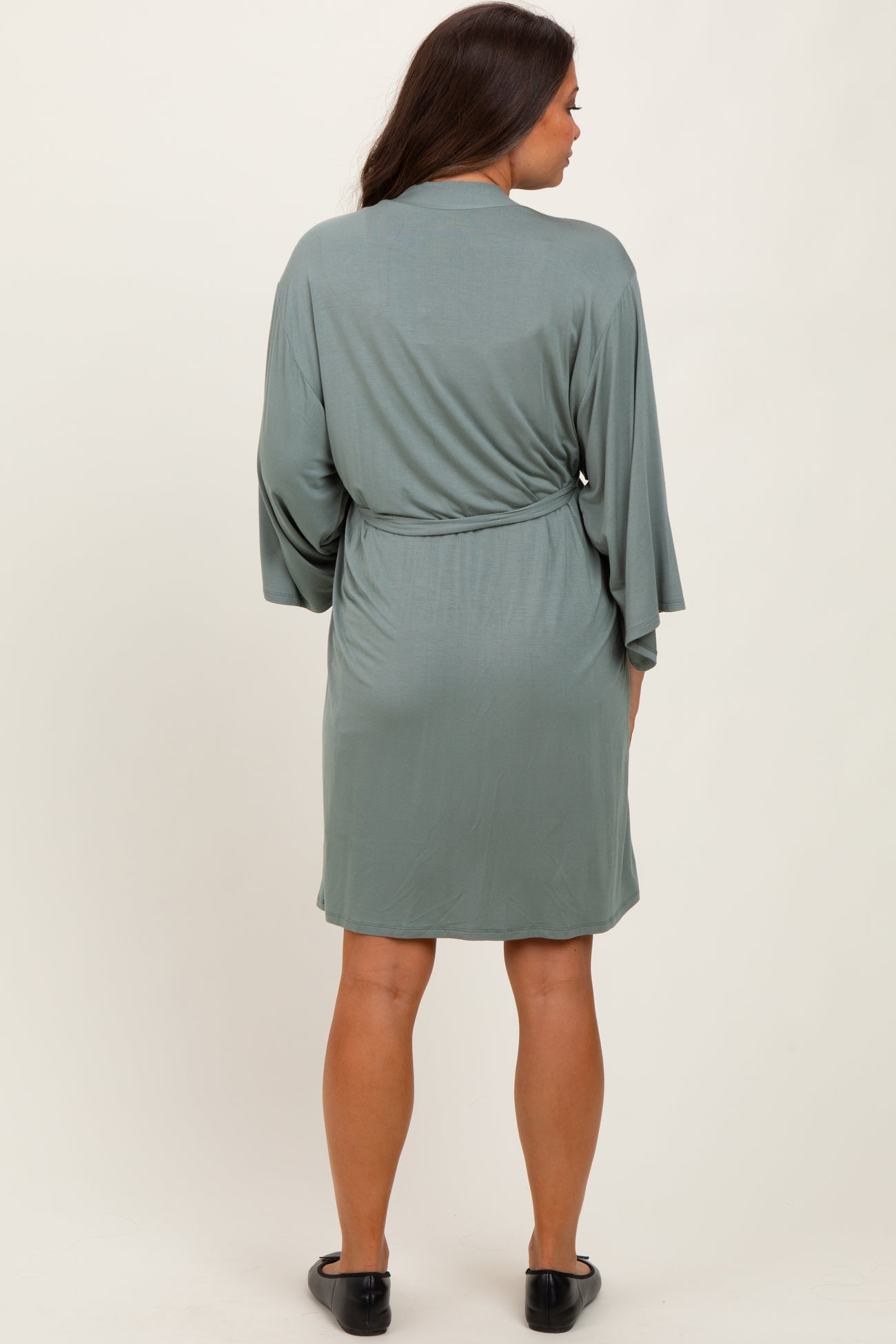 woman wearing a sage green maternity wrap dress with loose sleeves and gathered waist, showing a baby bump
