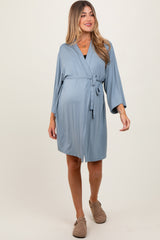 woman wearing a light blue maternity robe with a tie waist and kimono sleeves, showcasing her baby bump