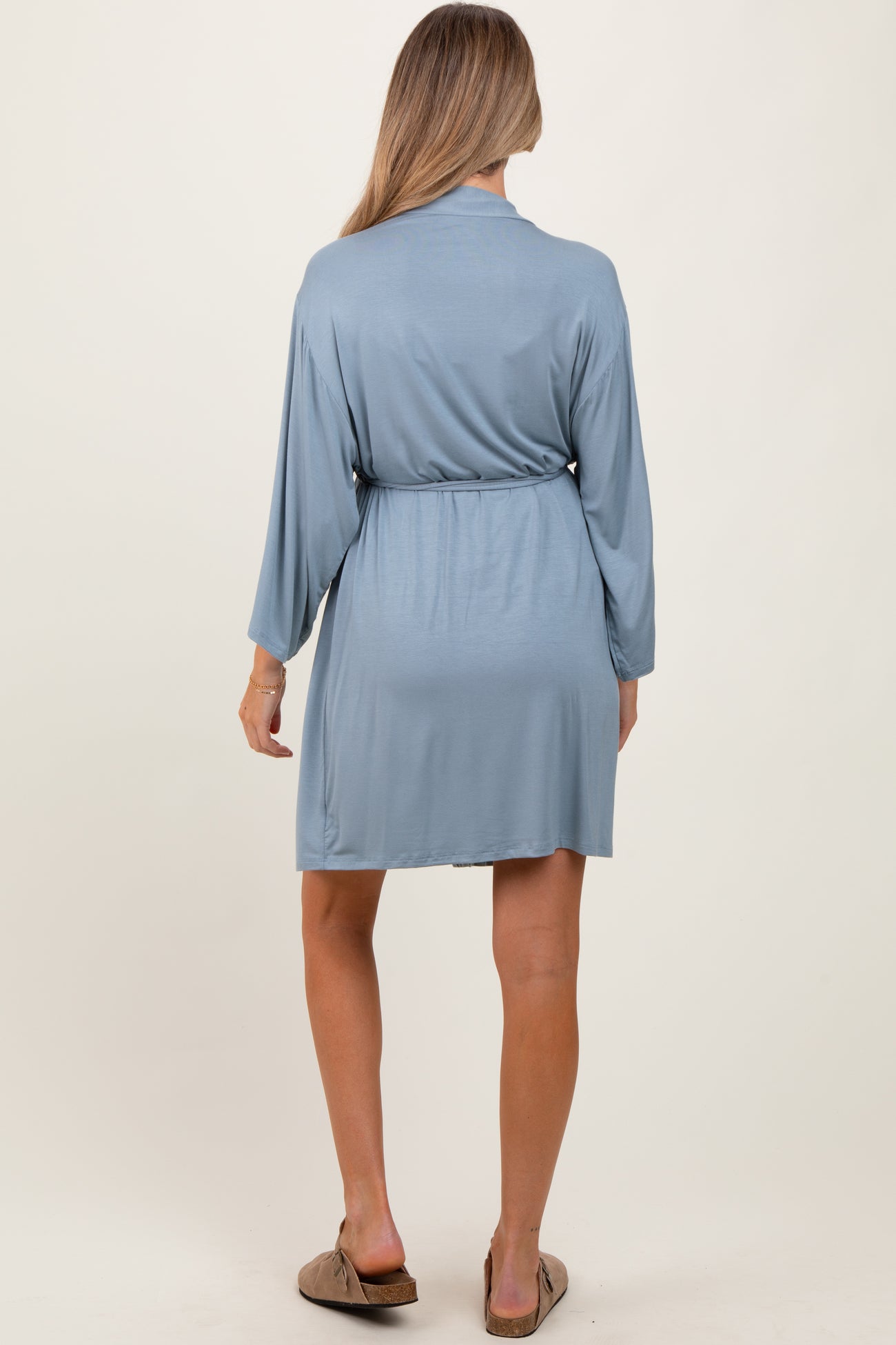 woman wearing a light blue maternity robe with long sleeves and a tie waist from the back