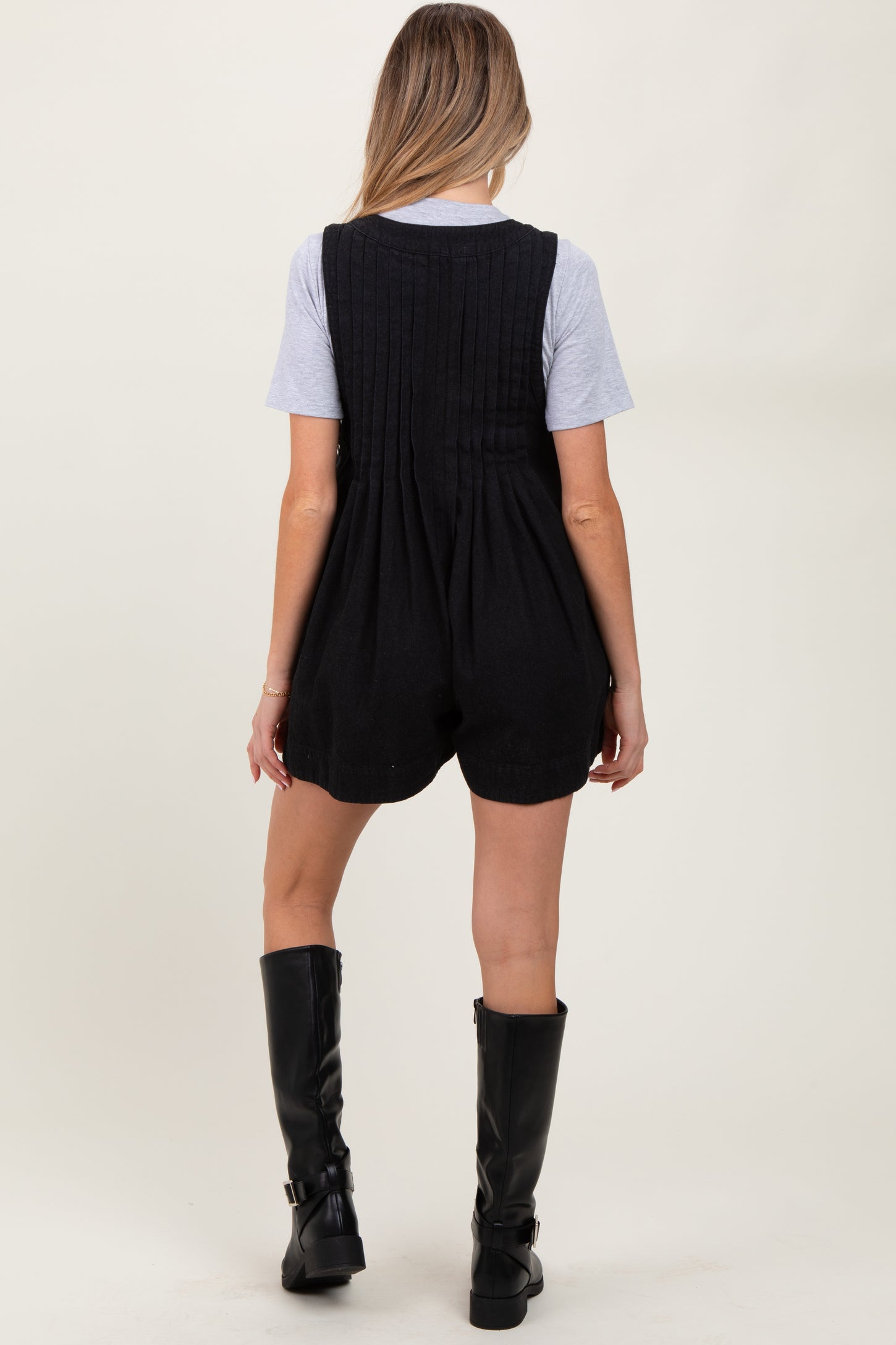 woman wearing a black maternity romper with a textured back and a gray t-shirt underneath