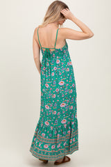 woman wearing a green floral maxi dress with a tiered skirt and spaghetti straps, showing the back view