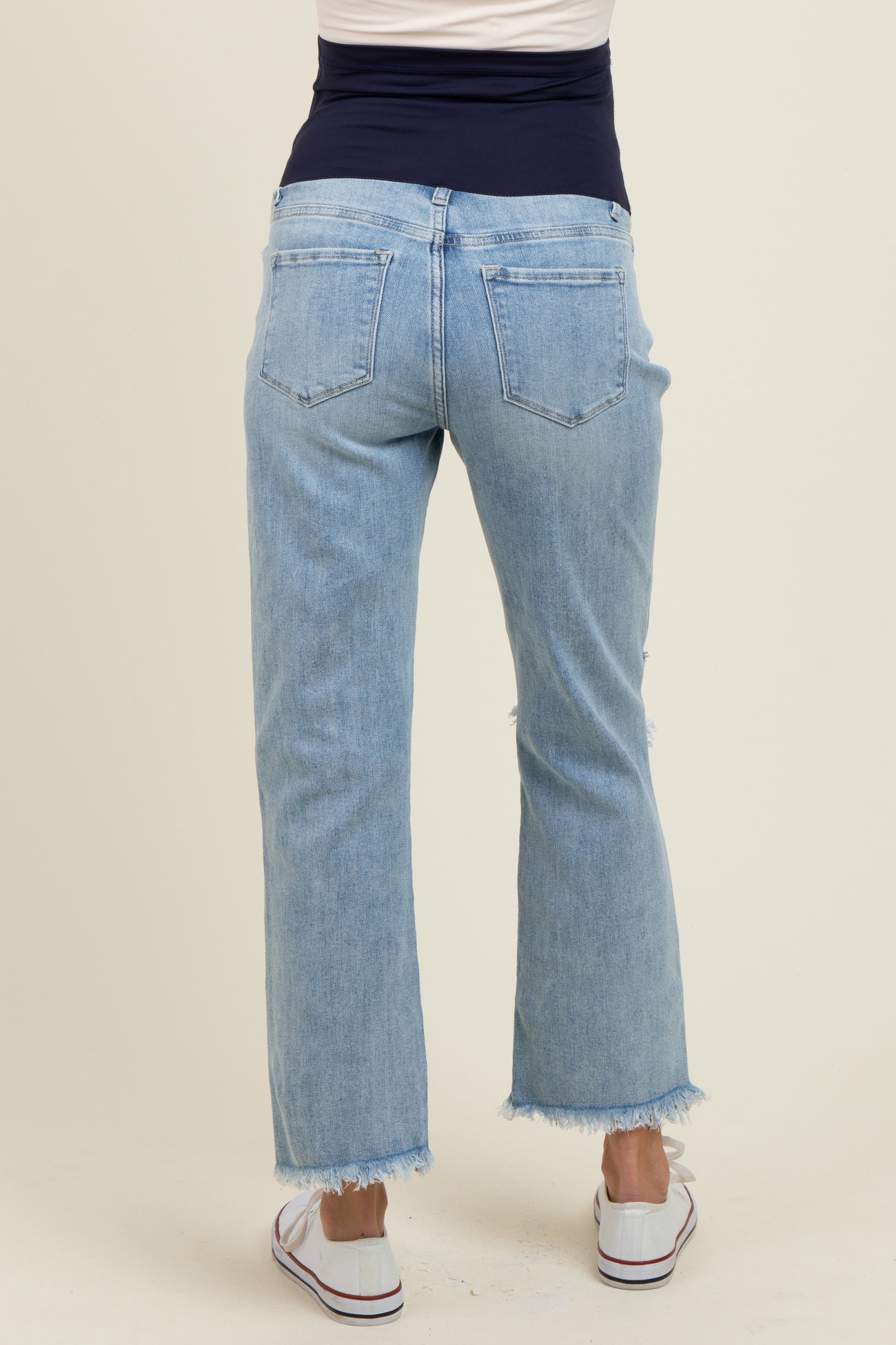 woman wearing light blue maternity jeans with a frayed hem, showing the back view, ideal for comfort during pregnancy