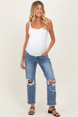 woman wearing a white maternity tank top and distressed blue jeans, showcasing her baby bump