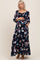 woman wearing a black floral print maternity maxi dress with long sleeves and pockets, showing her baby bump